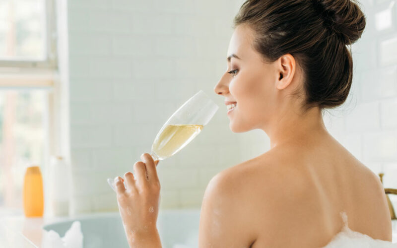 Frau trinkt Champagner in der Badewanne